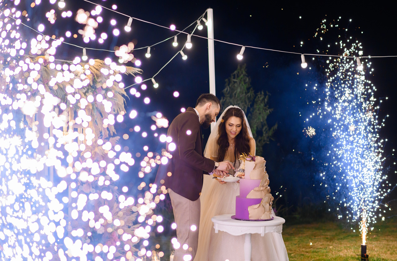 Молодожены на вечернем праздновании свадебного торта на открытом воздухе
